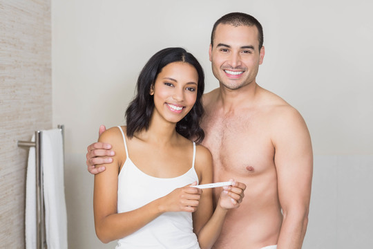 一对微笑的夫妇在浴室看怀孕测试