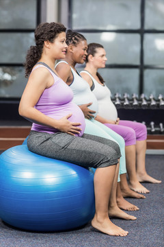 孕妇坐在健身球和触摸肚子上