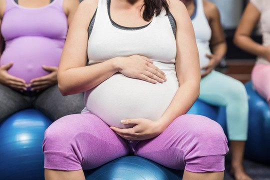孕妇坐在健身球和触摸肚子上
