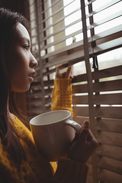 黑发女人喝着咖啡看着窗户