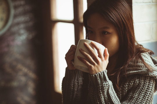 黑发女人坐在厨房的柜台上喝茶