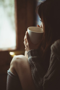 黑发女人坐在厨房的柜台上喝茶