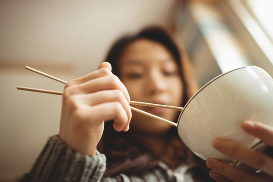 黑发女人在厨房用筷子吃饭