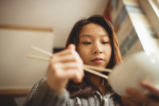 黑发女人在厨房用筷子吃饭