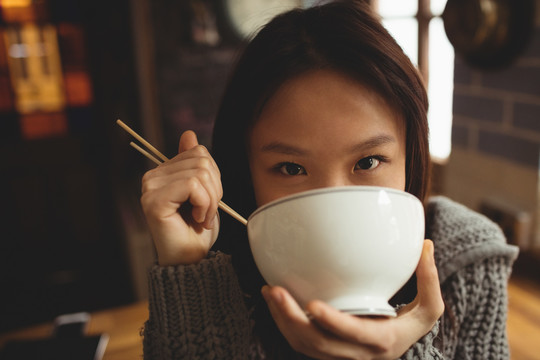 黑发女人在厨房用筷子吃饭