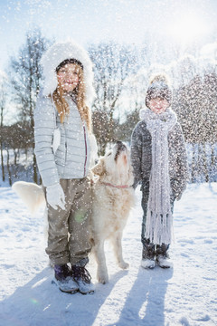 兄弟姐妹在美丽的雪天和狗玩耍