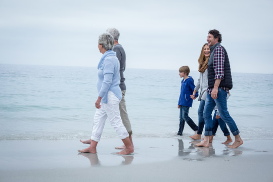 快乐的多代家庭在海边漫步