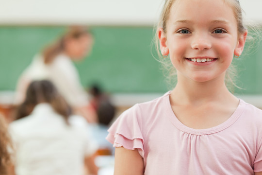 快乐微笑的小女孩站在教室里