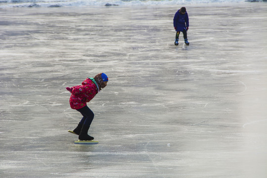 滑冰场上弯腰滑冰的小女孩