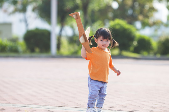 一个女孩子拿着纸飞机在公园玩耍