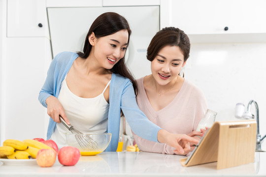 年轻女子在厨房边做饭边和朋友聊天