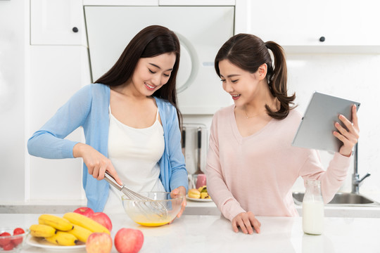 年轻女子在厨房边做饭边和朋友聊天