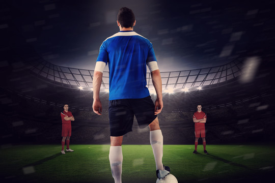 蓝色球衣的足球运动员面对足球场