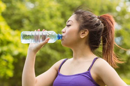 从瓶子里喝水的运动型女人