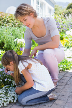 母亲和女儿在花园里照料外面的花