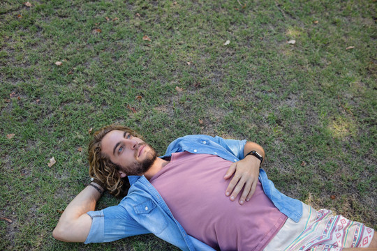 男人躺在公园的草地上听音乐