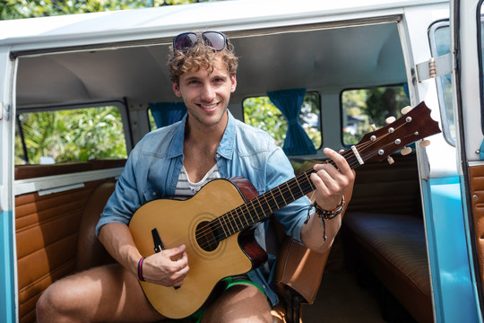在露营车里弹吉他的微笑男子