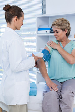 女医生在医院检查病人的血压
