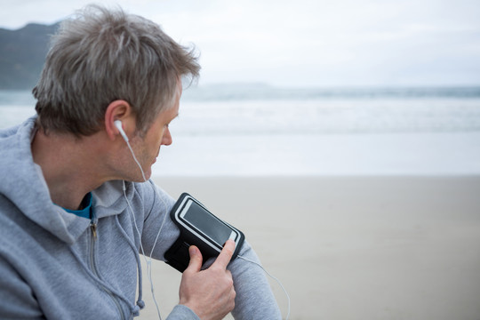 海滩上戴耳机听音乐的英俊男子