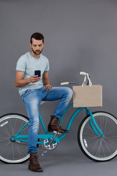 坐在自行车上使用手机的男人