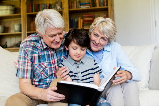 祖父母和孙子在家客厅拿书的照片