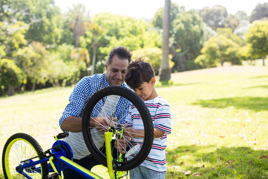男孩和父亲在公园修自行车