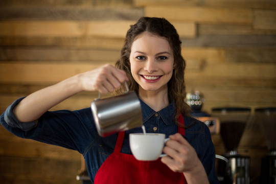 微笑的女服务员在咖啡馆里煮咖啡