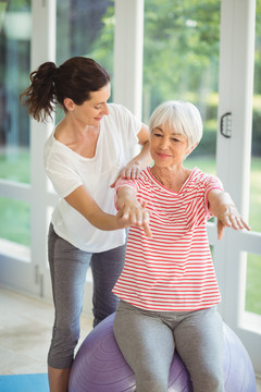 女教练协助老年妇女在家做运动