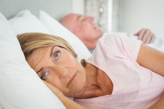 快乐的老年夫妇躺在卧室的床上