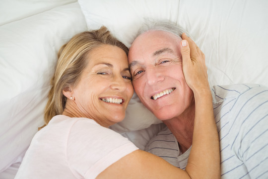 快乐的老年夫妇躺在卧室的床上