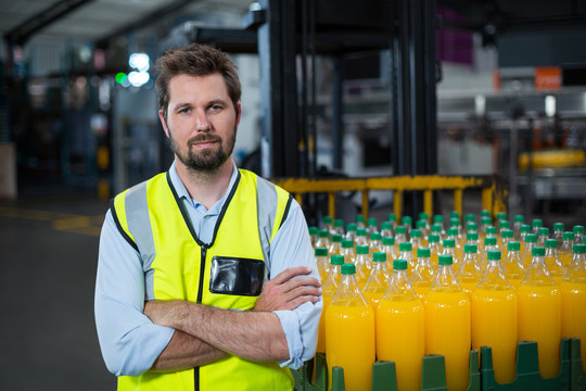 工厂工人倚靠在橙汁瓶板条箱上