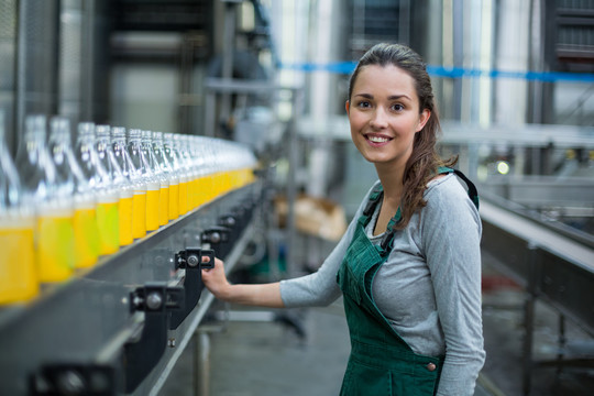 女职工在饮料生产厂检查生产线