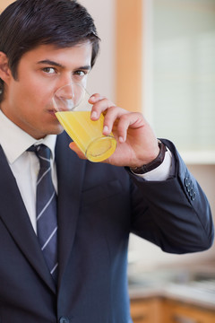 在厨房喝橙汁的商人的照片