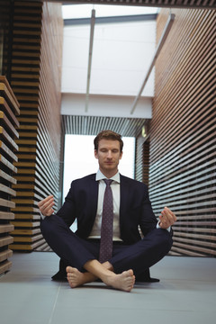 在办公室走廊里做瑜伽的商人
