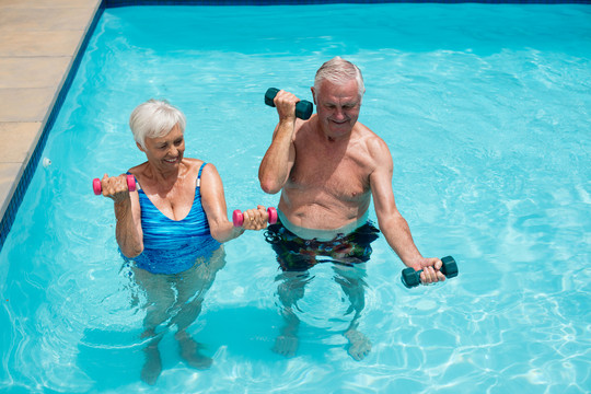老年夫妇在游泳池里用哑铃锻炼