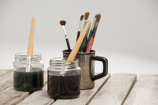 木桌上的两罐水彩画和油漆刷