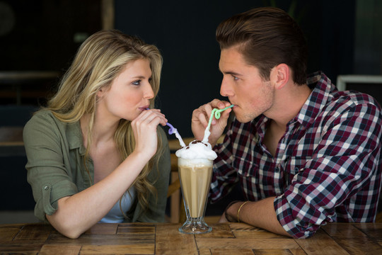 年轻夫妇在咖啡店的桌子上喝奶昔