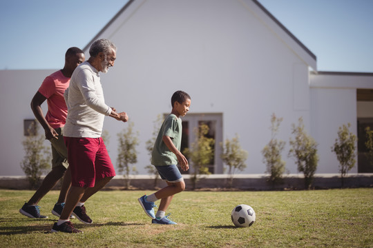 男孩与他的父亲和孙子踢足球