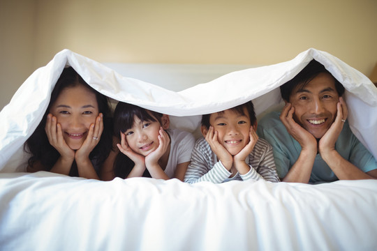 一家人在臥室的毯子下一起放松