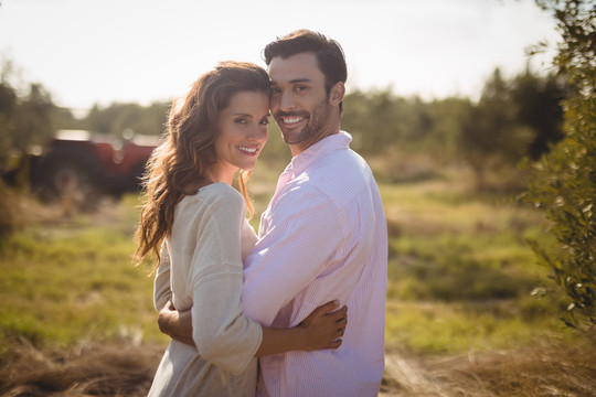 在橄榄农场拥抱的年轻夫妇