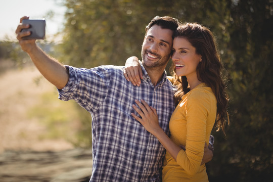 微笑的年轻夫妇在橄榄农场自拍