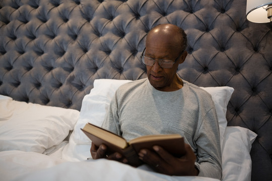 老人坐在卧室读书