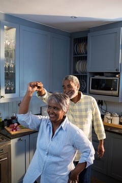 快乐的老年夫妇在家里的厨房跳舞