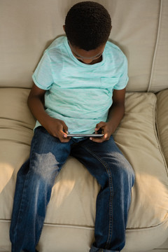 沙发上使用手机的男孩