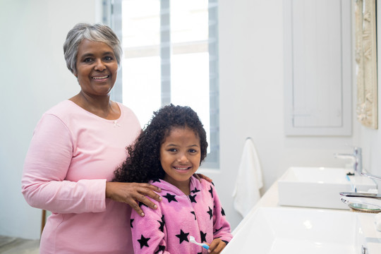 微笑的孙女和祖母站在家里浴室里