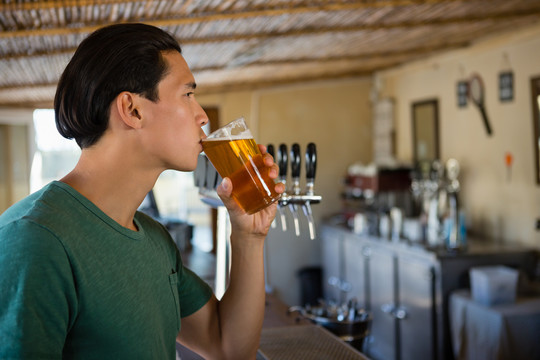 在酒吧喝啤酒的年轻人的肖像