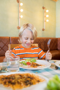 微笑的男孩坐在餐馆吃饭