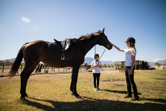 两个女孩牵着一匹马站在牧场上
