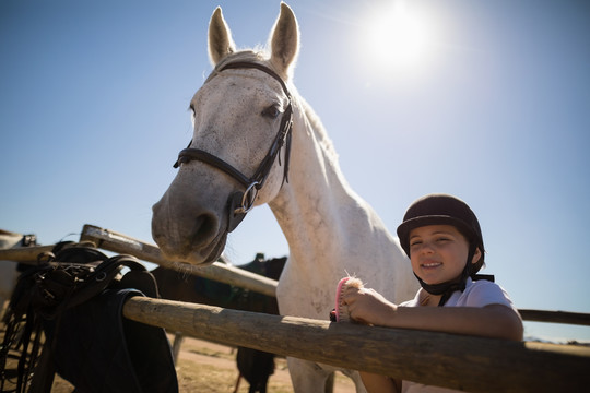 站在牧场白马旁边的微笑女孩