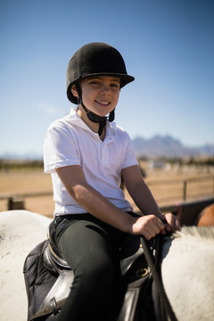 在牧场骑马的微笑女孩的肖像